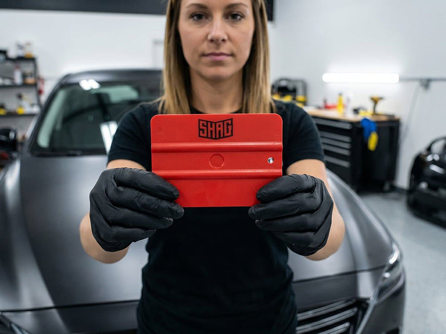 Hexis SHAG FRATERNITE red medium vinyl squeegee held by installer during vehicle wrap application