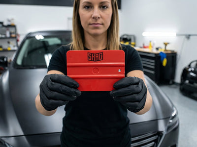 Hexis SHAG FRATERNITE red medium vinyl squeegee held by installer during vehicle wrap application