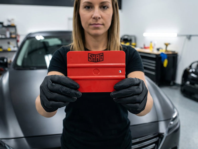 Hexis SHAG FRATERNITE red medium vinyl squeegee held by installer during vehicle wrap application