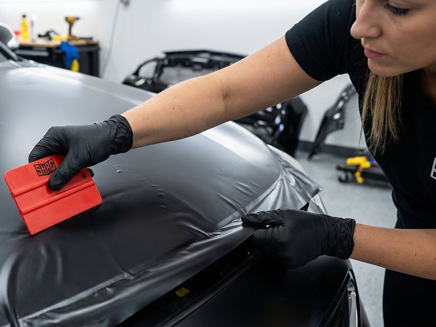 Hexis SHAG FRATERNITE red medium squeegee applying vinyl wrap on vehicle hood for smooth bubble-free installation